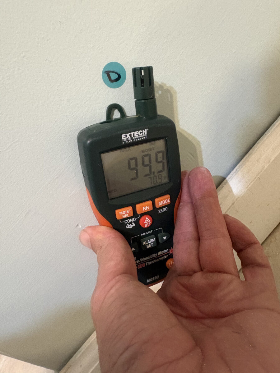 Moisture meter at 99.9% on a wall