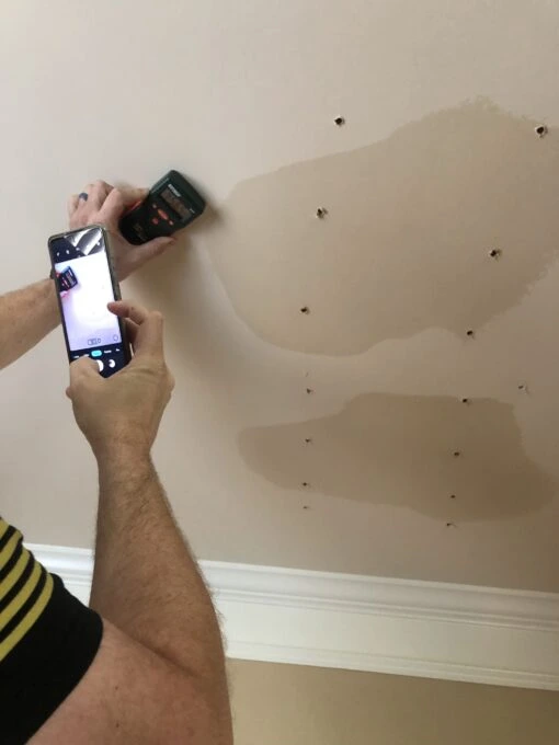 Testing a wet ceiling with a moisture meter during a Marietta water damage restoration inspection.